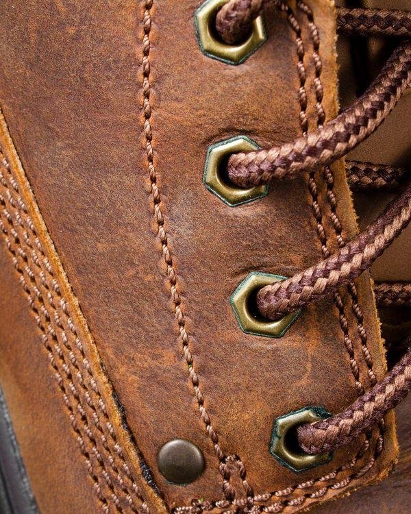 Detail of a tan leather boot showing brass eyelets and welted stitching.